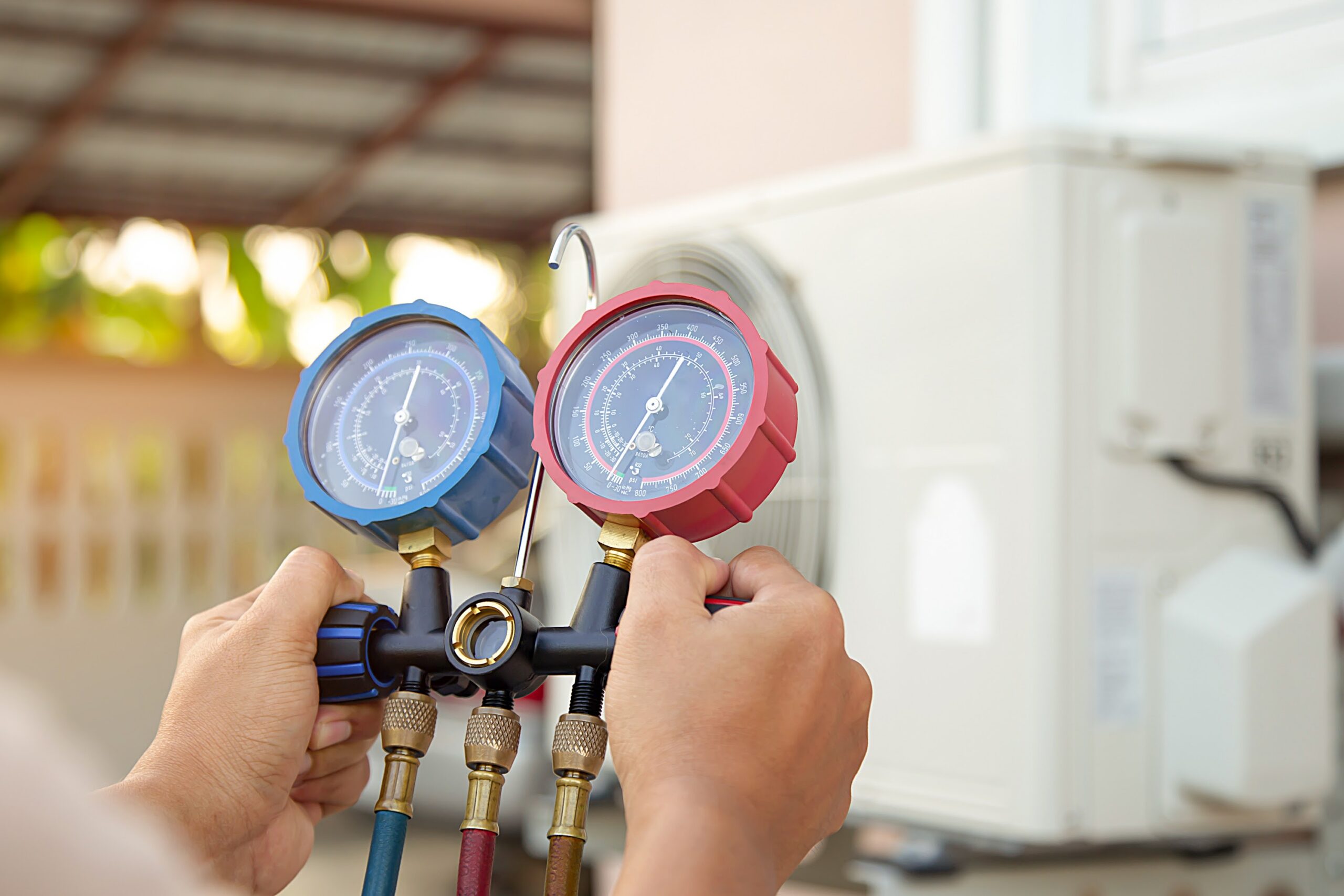 Hands a technician using a measuring tool to check that the vacuum pump evacuates air for air conditioner.